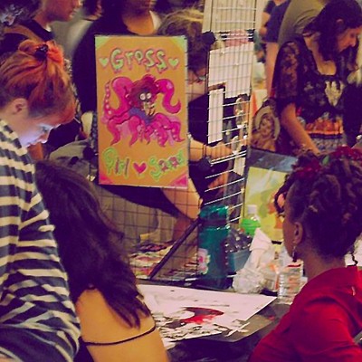 A room full of people browse zines displayed on tables