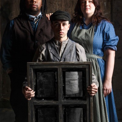 A portrait of three people posed in old-fashioned clothing