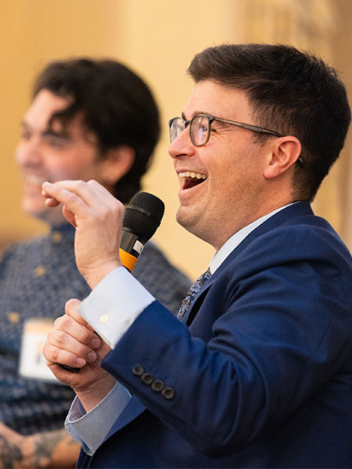 Two men laugh while holding microphones