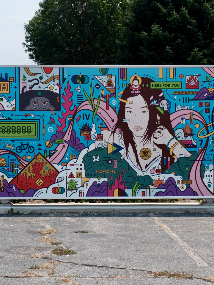Colorful mural of a woman surrounded by abstract shapes, symbols, and vibrant patterns outdoors.