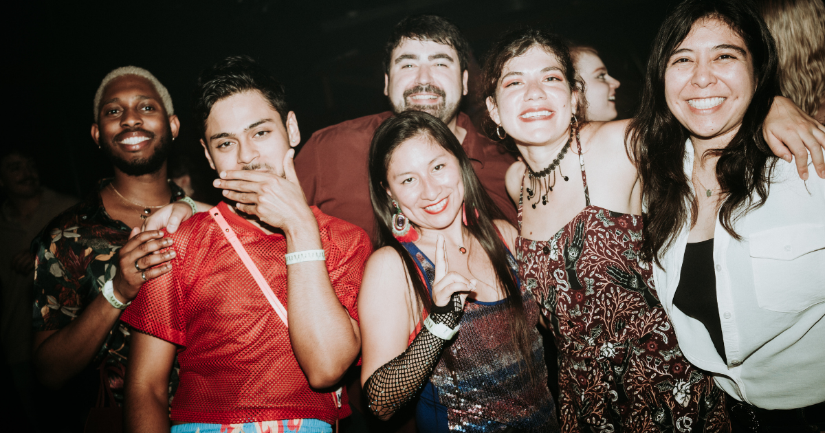 A group of six people pose and smile together at a party.