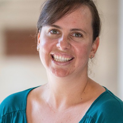 An image of Allison Popieski, a caucasian woman with brown hair, brown eyes, and a big smile. She wears a teal shirt.