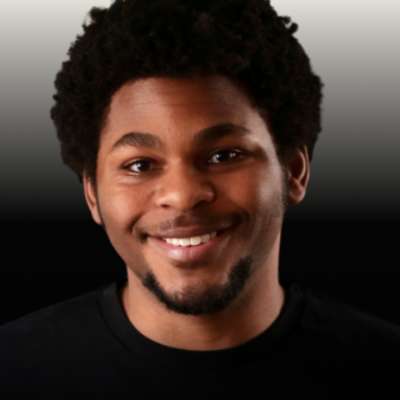 Smiling portrait of a person with short, curly dark hair and a trimmed goatee, wearing a black shirt