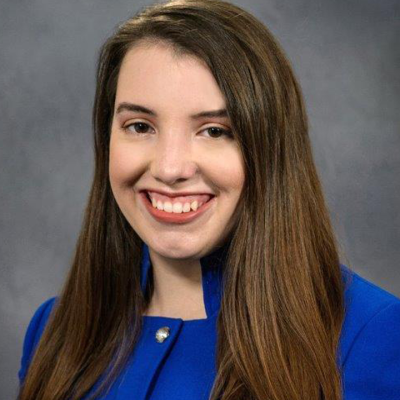 Smiling portrait of woman with long brown hair, wearing a bright blue suit