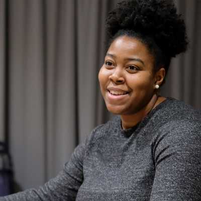 Mary C. Parker, a smiling Black woman with her hair pulled up, gesturing happily.