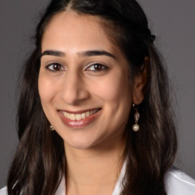 Smiling portrait of a woman with long brown hair wearing white scrubs