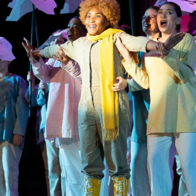 A group of performers sings on stage holding props shaped like birds.