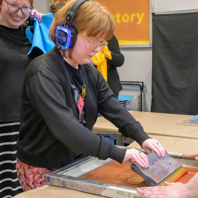 People work together on a screen printing project in a classroom setting.