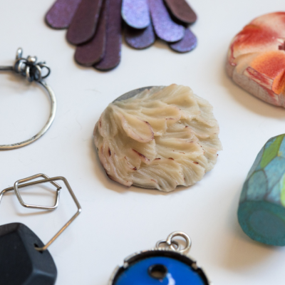 Assorted handmade jewelry pieces and charms displayed on a white surface.