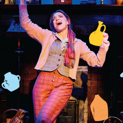 Woman singing on stage, holding illustrated pitchers, with a cozy set and warm blue lighting.