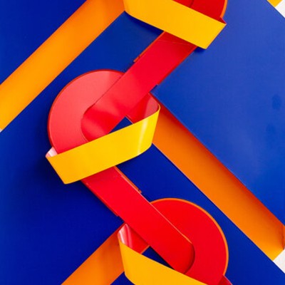 A brightly colored blue, red, and yellow abstract folded-metal sculpture