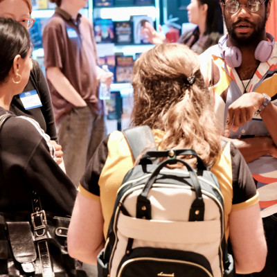A group of people talking inside a bookstore near a display of books.