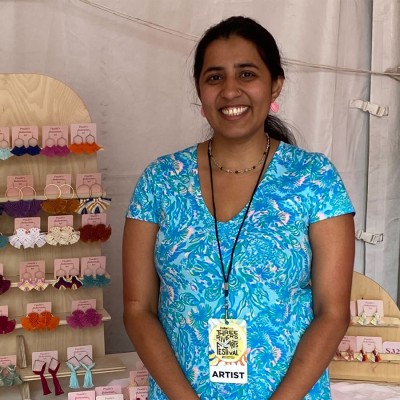 A woman smiles next to handmade jewelry