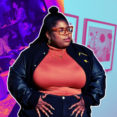 A woman in glasses and a jacket stands confidently against a vibrant background.