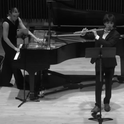 A pianist and a flutist perform together on stage in a concert hall.