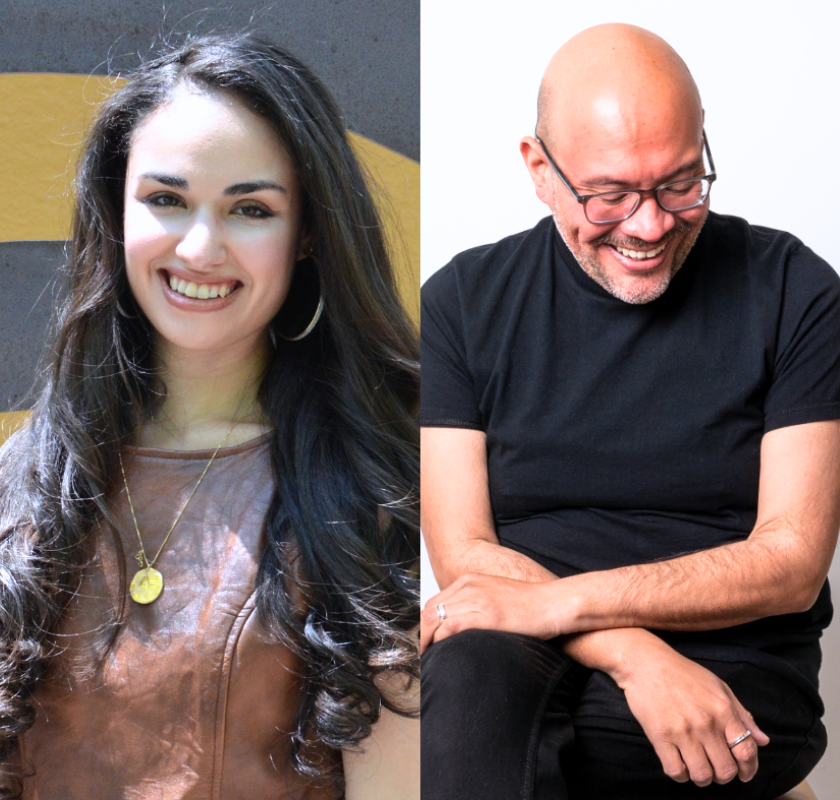 A woman smiling next to a man sitting and laughing against a white background.