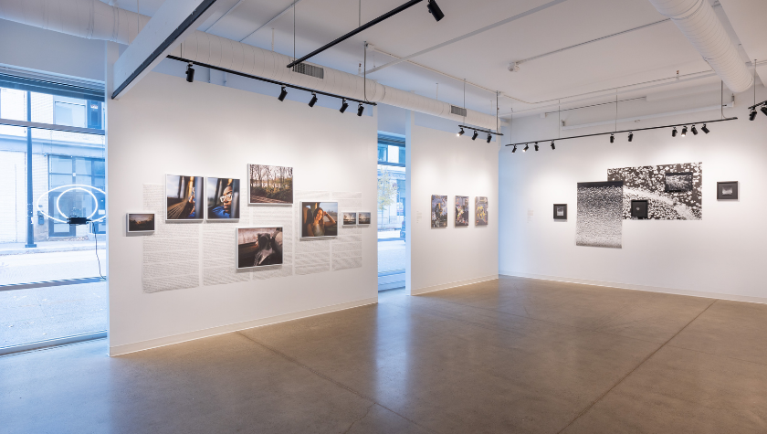 A modern art gallery with photos and artworks displayed on white walls.