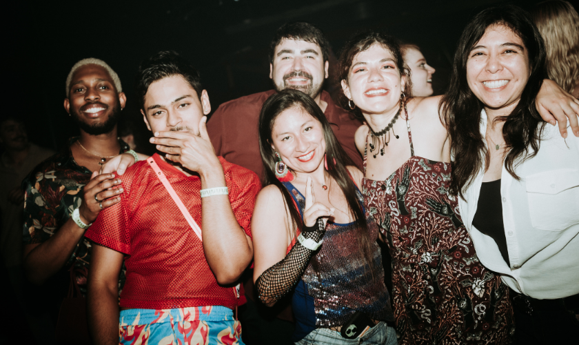 A group of six people pose and smile together at a party.