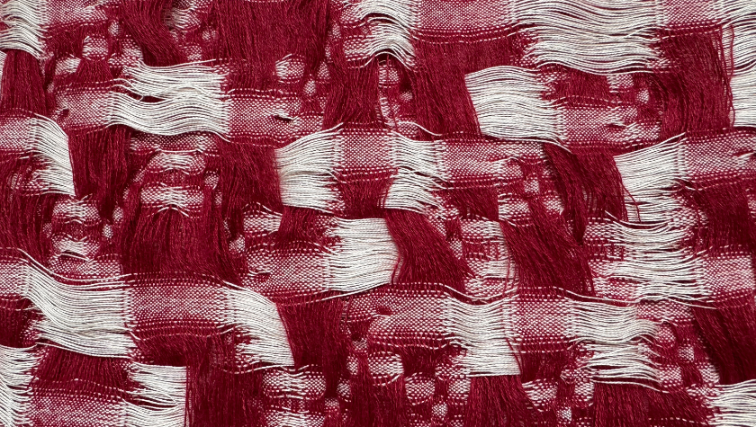 Red and white woven textile with textured, undulating patterns.