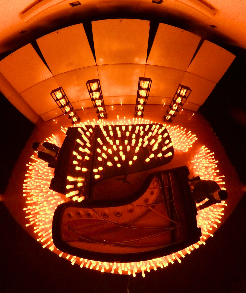 Overhead view of two grand pianos surrounded by glowing orange lights.