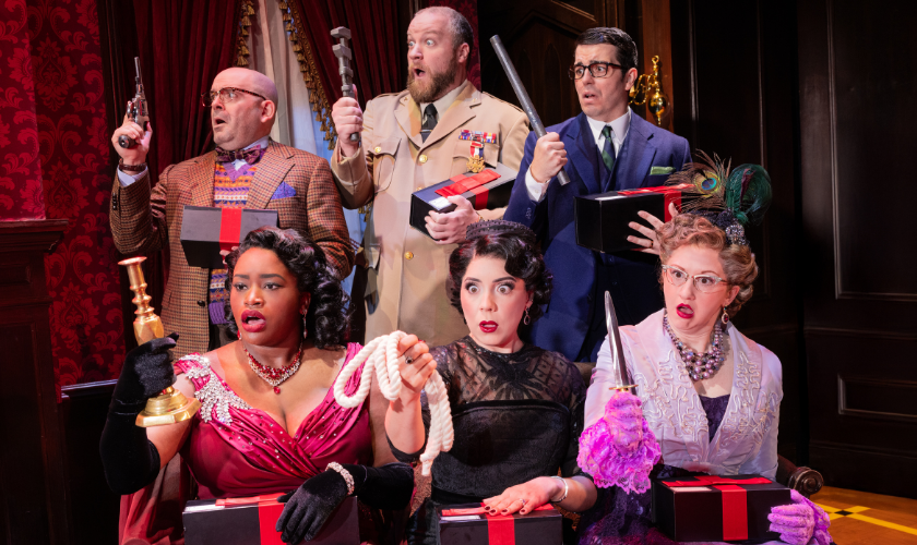 Six people in costumes hold various weapons and black boxes in a dramatic scene.