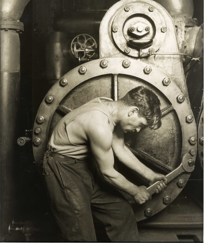 Man using a large wrench to adjust machinery in an industrial setting.