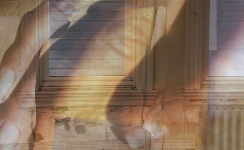 Sunlit, peeling paint on a wall with windows and a radiator, layered with abstract shadows.