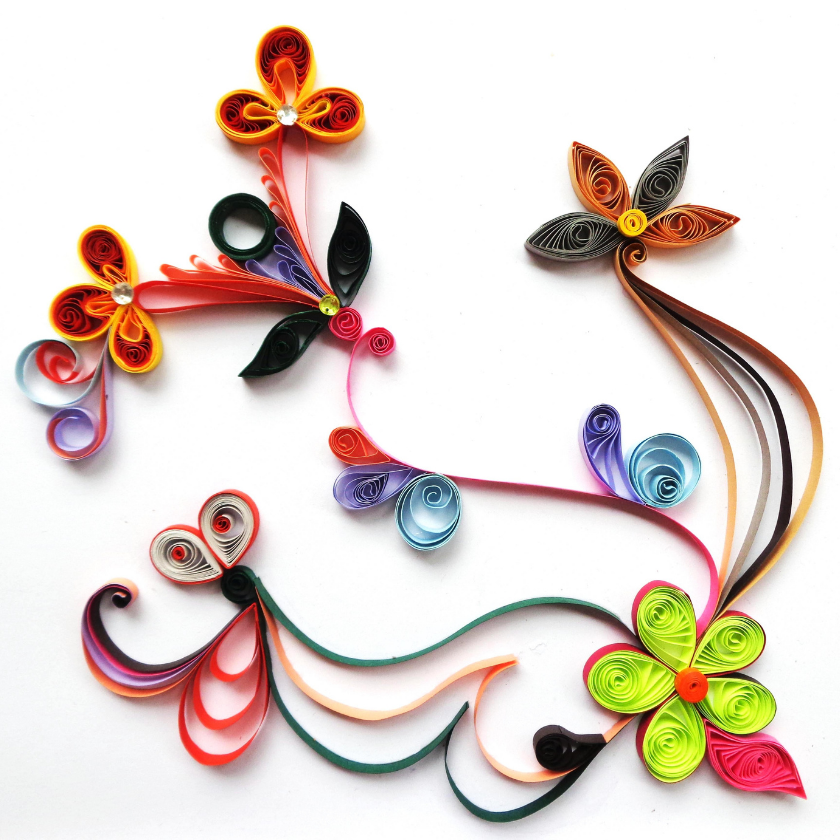 Colorful quilled paper flowers and swirls arranged on a white background.