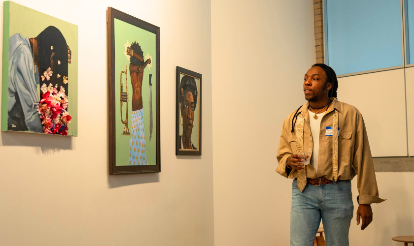 A person observes three colorful portraits hung on a white gallery wall.