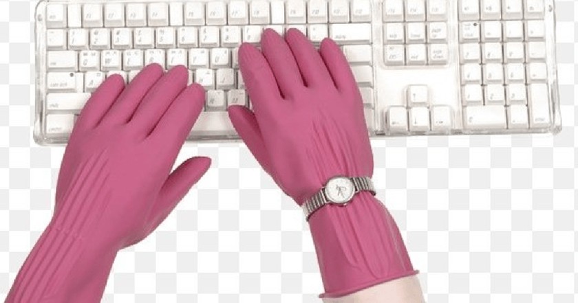 A pair of hands are typing on a white keyboard. The hands are wearing pink plastic gloves. The right hand has on a watch over top of the glove. In the background is a gray-and-white checkboard pattern mimicking a computer image