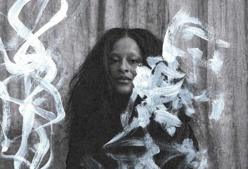 Person with long hair sits behind sheer paint strokes on a textured background.