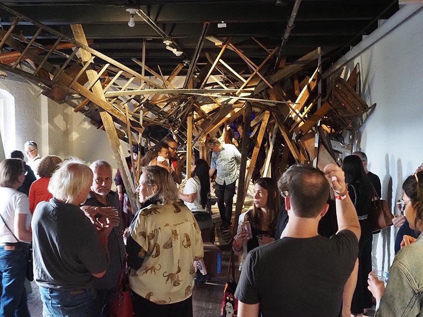 A crowd of people look at a large inside art installation