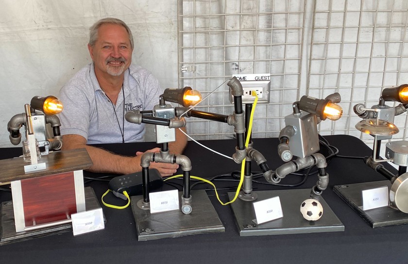 Smiling man sits in front of display of artistic lighting features