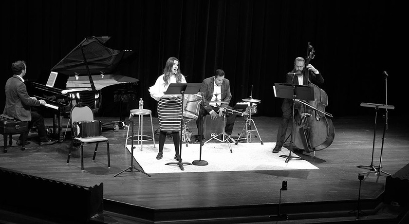 Black-and-white photo of musicians in a chamber orchestra performing on stage