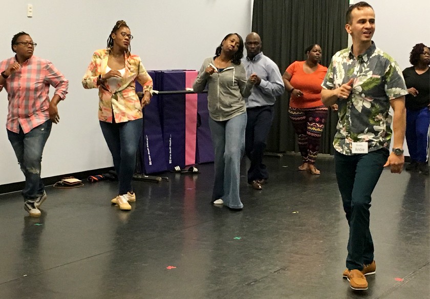 Seven people stand in a row dancing