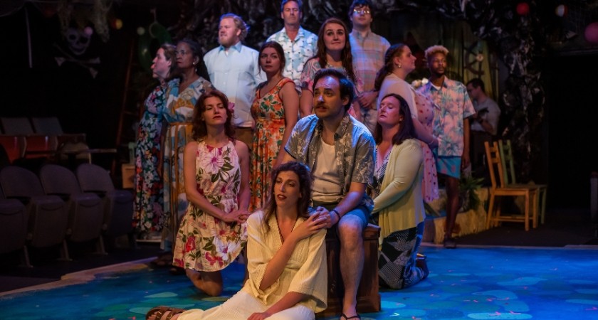 A photo of a group of actors on stage standing in a circle