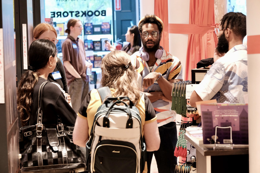A group of people talking inside a bookstore near a display of books.