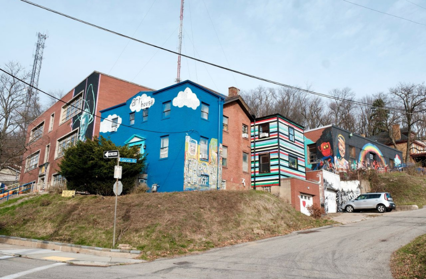 Buildings with colorful murals and street art on a sloped neighborhood street