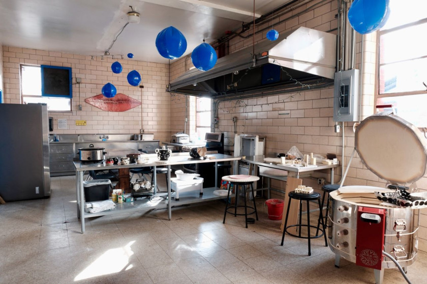 Ceramics studio with worktables, pottery tools, blue balloons, and a kiln.