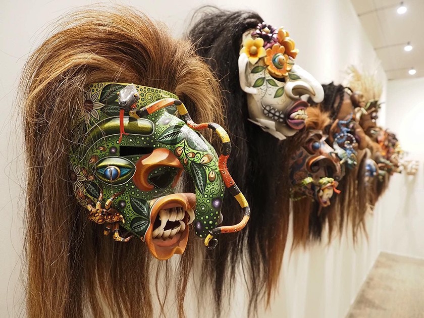 A group of Mexican masks hanging on a museum wall