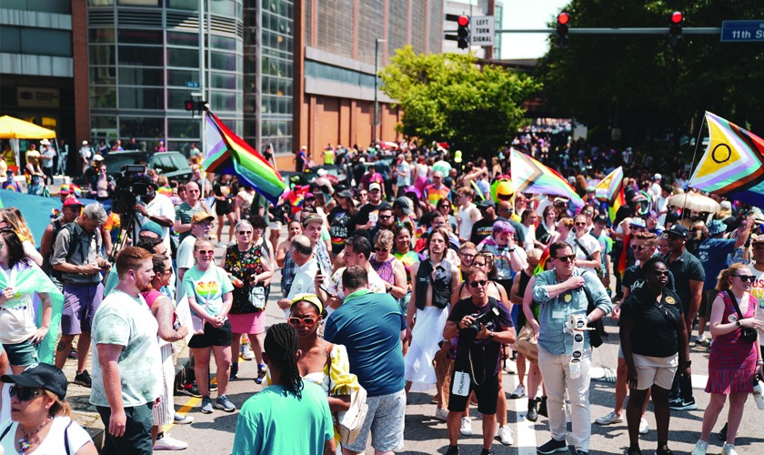 A parade full of people holding rainbow flags