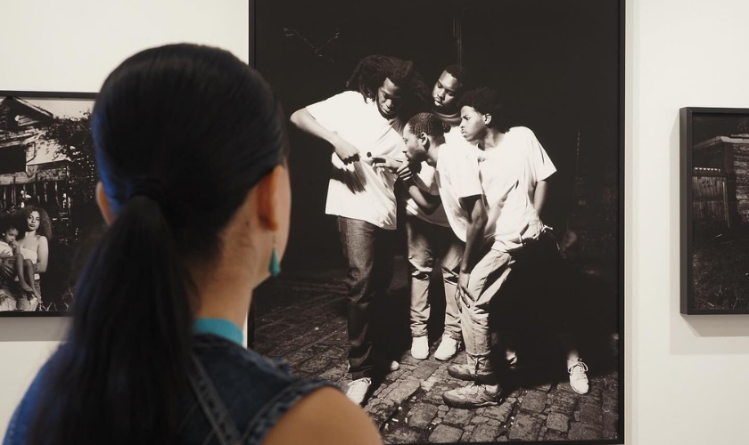 A woman looks at a black-and-white photograph displayed on a gallery wall