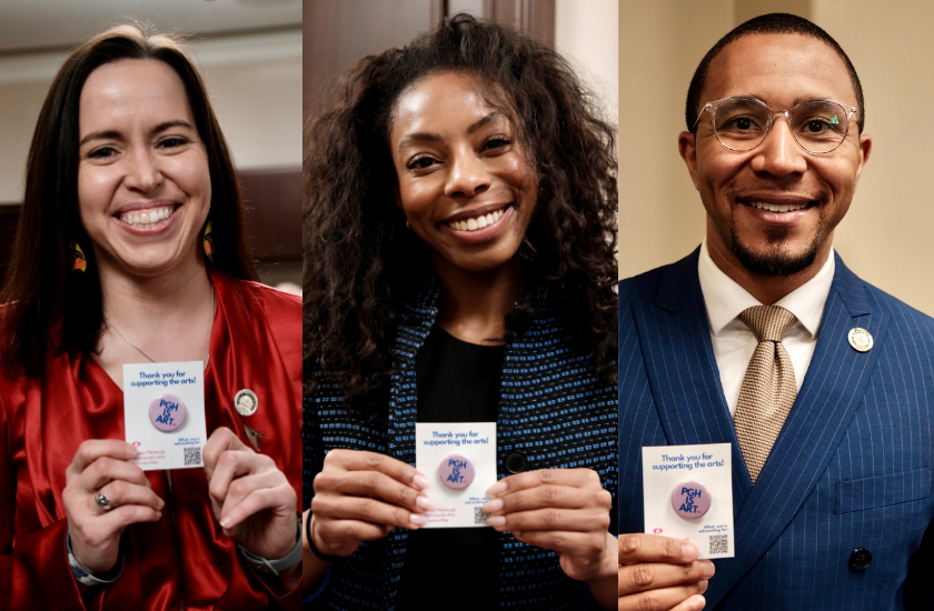 Three smiling people hold Thank you for supporting the arts! cards and pose for the camera.