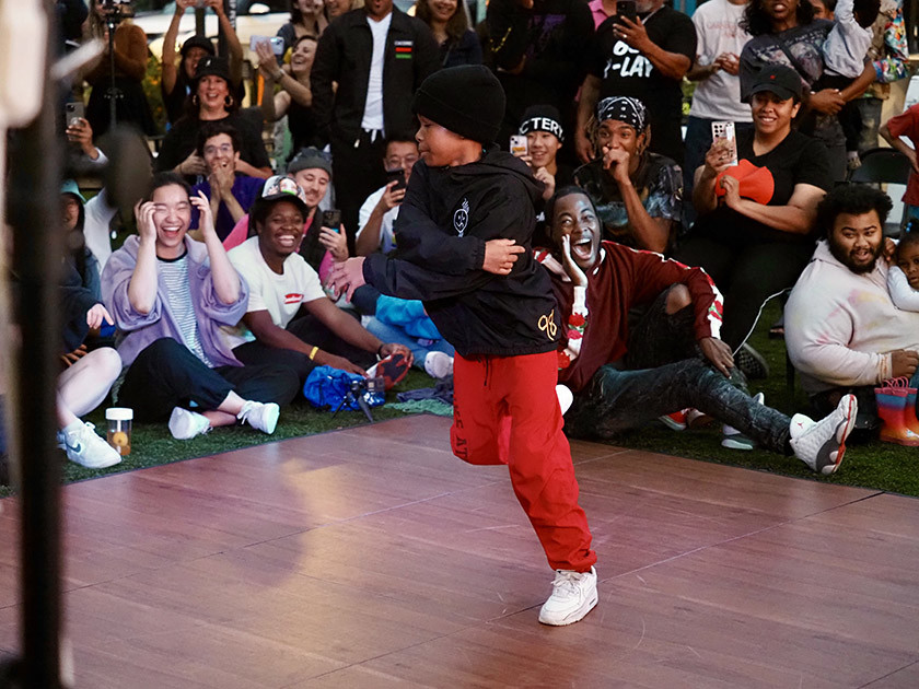 A small boy dances on stage in front of a cheer audience