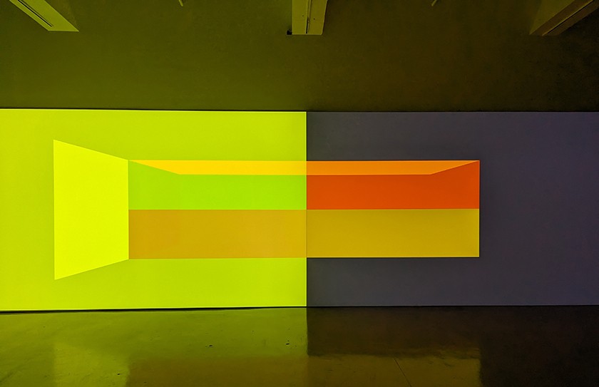 Bright blocks of colored light are projected onto a gallery wall