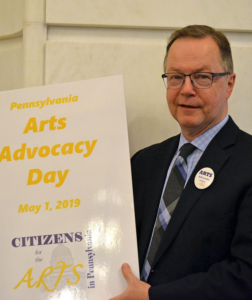 CEO Mitch Swain poses with a sign that says "Arts Advocacy Day, May 1, 2019"