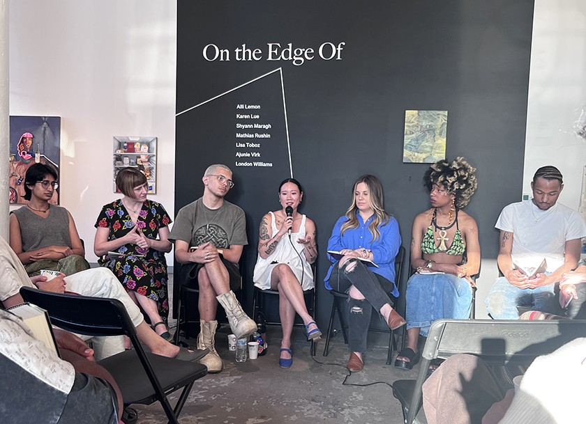 	 Seven people sit in a row on stage having a panel discussion. One person in the center is speaking into a microphone. Behind them is a black wall with the text On the Edge Of and a list of names.