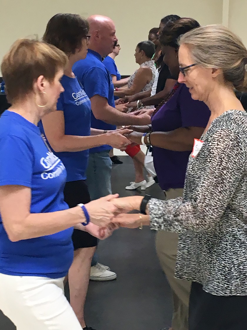 Two rows of people hold hand dancing